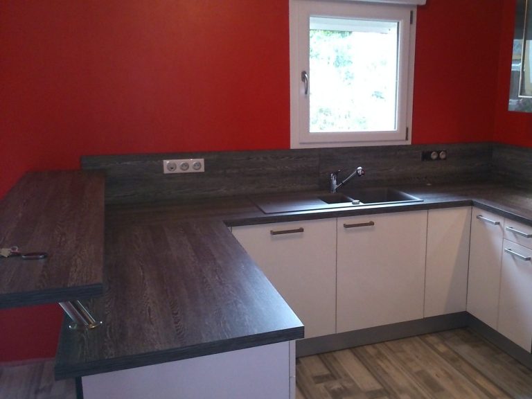 Moderne Küche mit roter Wand, Holzarbeitsplatte und Fensterlicht.